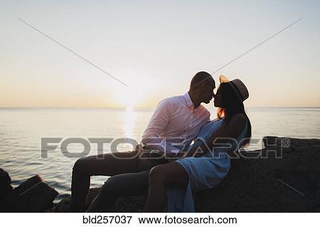 Caucasian couple rubbing noses near ocean at sunset View Large Photo Image Stock Photo - Caucasian couple rubbing noses near ocean at sunset. Fotosearch