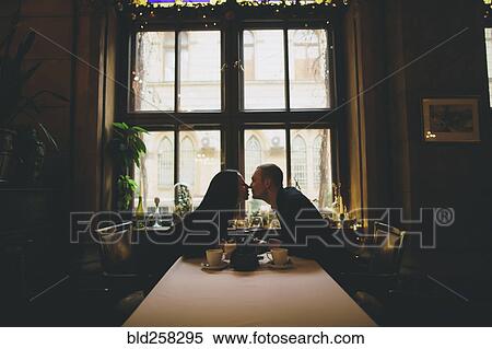 Stock Photography - Caucasian couple sitting at table rubbing noses. Fotosearch