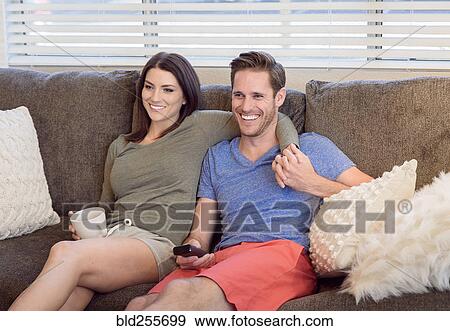 Caucasian couple sitting on sofa watching television View Large Photo Image Stock Photo - Caucasian couple sitting on sofa watching television. Fotosearch