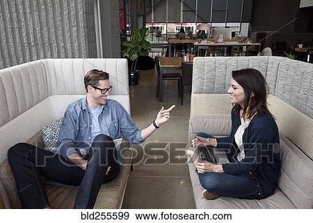 Stock Photo - Caucasian couple sitting on sofas talking. Fotosearch