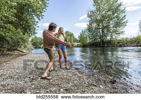 Caucasian couple skipping stones in river View Large Photo Image Stock Photo - Caucasian couple skipping stones in river. Fotosearch