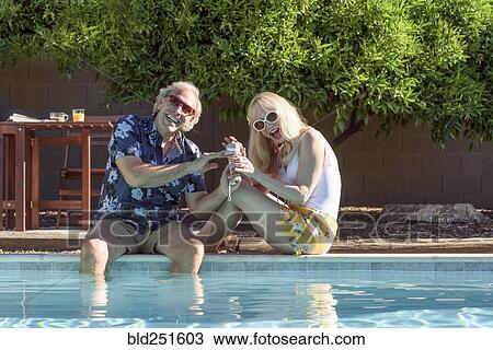 Stock Image - Caucasian couple smiling near swimming pool. Fotosearch