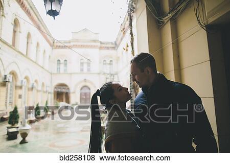 Stock Photo - Caucasian couple standing face to face in courtyard. Fotosearch