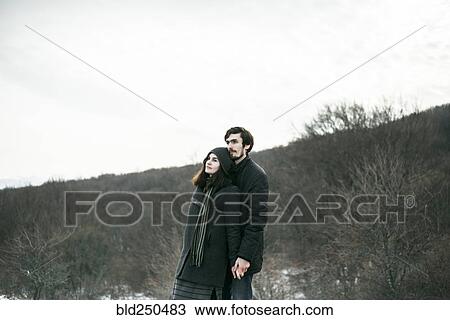 Stock Image - Caucasian couple standing on hill and relaxing. Fotosearch