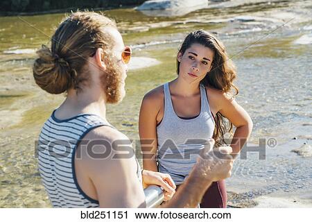 Stock Image - Caucasian couple talking near river. Fotosearch