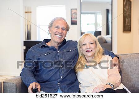 Stock Photo - Caucasian couple watching television in livingroom. Fotosearch