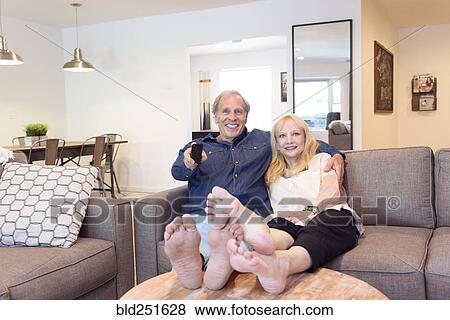 Caucasian couple watching television in livingroom View Large Photo Image Stock Photo - Caucasian couple watching television in livingroom. Fotosearch