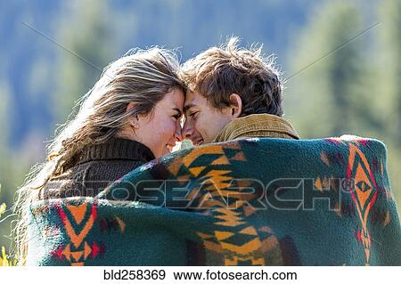 Stock Photo - Caucasian couple wrapped in blanket rubbing noses. Fotosearch