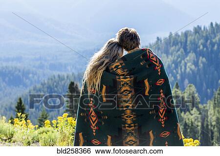 Caucasian couple wrapped in blanket admiring scenic view of landscape View Large Photo Image Stock Photograph - Caucasian couple wrapped in blanket admiring scenic view of landscape. Fotosearch
