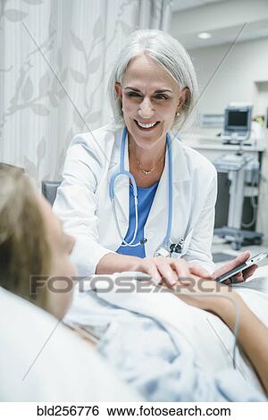 Stock Photograph - Caucasian doctor comforting girl in hospital bed. Fotosearch