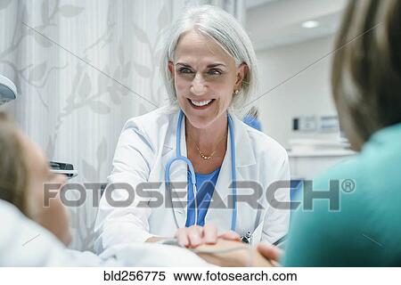 Stock Photography - Caucasian doctor comforting girl in hospital bed. Fotosearch