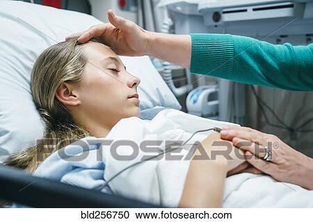 Stock Image - Caucasian doctor comforting patient in hospital bed. Fotosearch