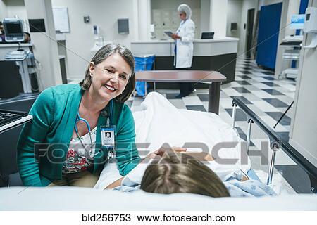 Stock Image - Caucasian doctor comforting patient in hospital bed. Fotosearch