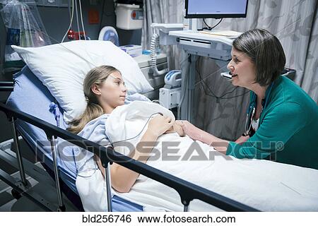 Stock Photograph - Caucasian doctor comforting patient in hospital bed. Fotosearch