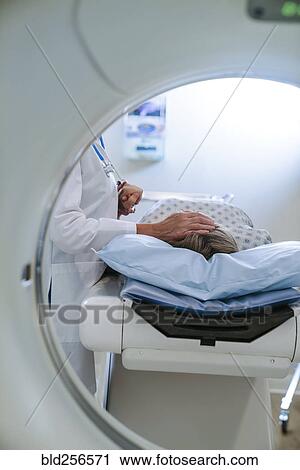 Stock Image - Caucasian doctor comforting patient near scanner. Fotosearch