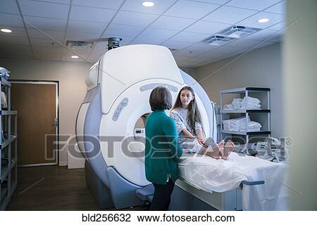 Stock Image - Caucasian doctor talking to patient at scanner. Fotosearch