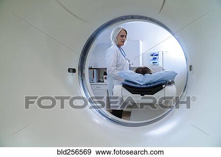 Stock Photo - Caucasian doctor talking to patient near scanner. Fotosearch
