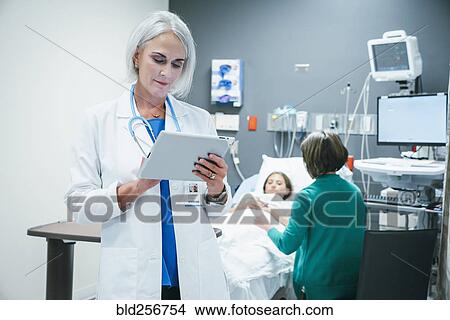 Caucasian doctor using digital tablet in hospital View Large Photo Image Picture - Caucasian doctor using digital tablet in hospital. Fotosearch