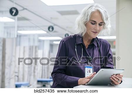 Stock Photography - Caucasian doctor using digital tablet in hospital. Fotosearch