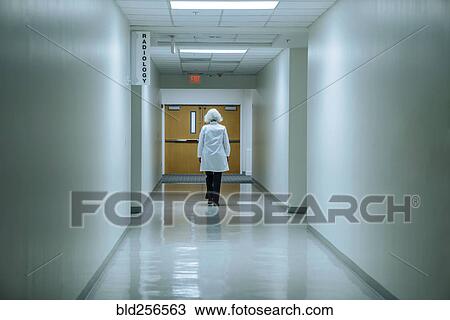 Stock Image - Caucasian doctor walking in hospital. Fotosearch