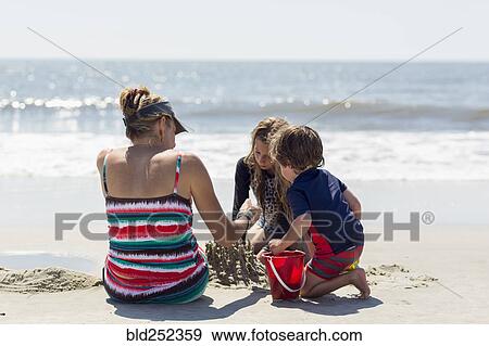 Caucasian family building sand castle at beach View Large Photo Image Stock Photo - Caucasian family building sand castle at beach. Fotosearch