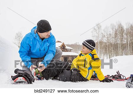 Caucasian father adjusting snowshoe for son View Large Photo Image Stock Photo - Caucasian father adjusting snowshoe for son. Fotosearch