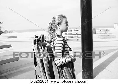 Stock Image - Caucasian girl carrying folding chair at beach. Fotosearch