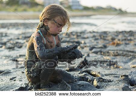 Caucasian girl covered in mud playing on beach View Large Photo Image Stock Photo - Caucasian girl covered in mud playing on beach. Fotosearch