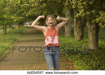 Stock Photo - Caucasian girl dancing in park listening to earbuds. Fotosearch