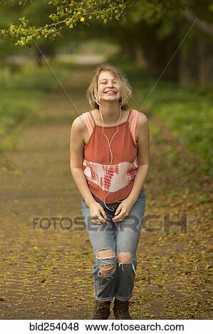 Stock Photo - Caucasian girl dancing in park listening to earbuds. Fotosearch