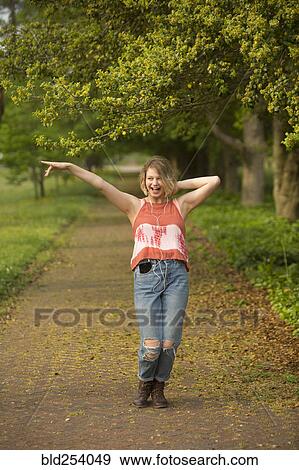 Stock Photo - Caucasian girl dancing in park listening to earbuds. Fotosearch
