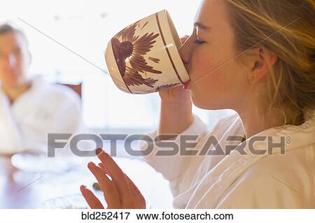 Stock Photo - Caucasian girl drinking coffee in bathrobe. Fotosearch