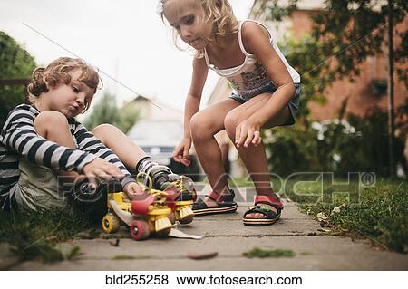 Caucasian girl helping boy with rollerskates View Large Photo Image Stock Photo - Caucasian girl helping boy with rollerskates. Fotosearch