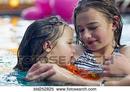 Stock Photography - Caucasian girl holding brother in swimming pool. Fotosearch