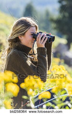 Picture - Caucasian girl in field using binoculars. Fotosearch