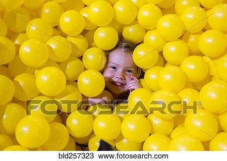 Caucasian girl laying in pile of yellow balls View Large Photo Image Stock Image - Caucasian girl laying in pile of yellow balls. Fotosearch