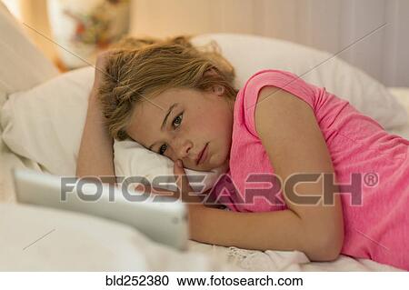 Caucasian girl laying on bed watching digital tablet View Large Photo Image Stock Image - Caucasian girl laying on bed watching digital tablet. Fotosearch