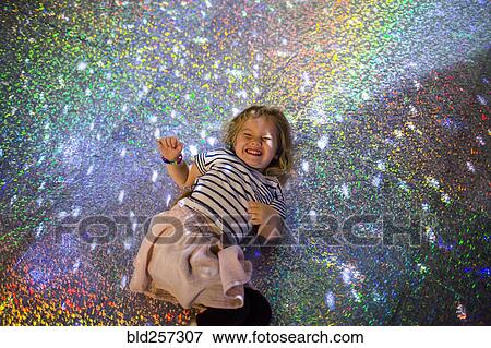 Stock Photo - Caucasian girl laying on floor under disco ball. Fotosearch