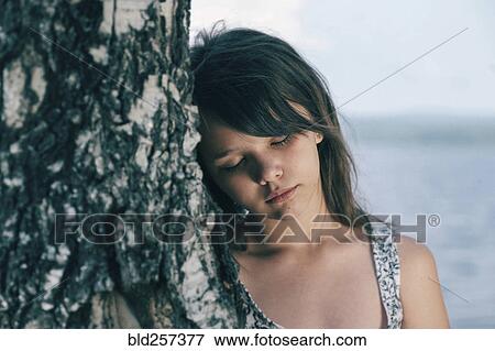 Caucasian girl leaning head on tree trunk View Large Photo Image Stock Photo - Caucasian girl leaning head on tree trunk. Fotosearch
