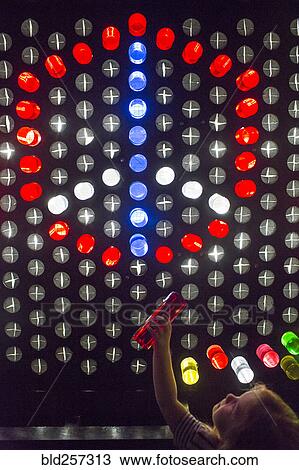 Stock Image - Caucasian girl placing colorful game pieces on puzzle wall. Fotosearch