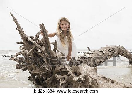 Caucasian girl posing on driftwood on beach View Large Photo Image Picture - Caucasian girl posing on driftwood on beach. Fotosearch