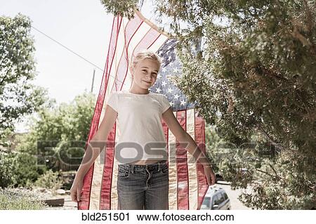 Stock Image - Caucasian girl posing with American flag. Fotosearch