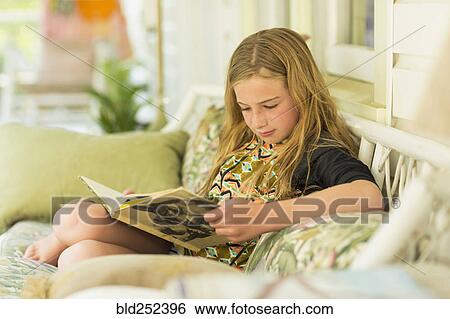 Caucasian girl reading book on sofa View Large Photo Image Stock Photograph - Caucasian girl reading book on sofa. Fotosearch