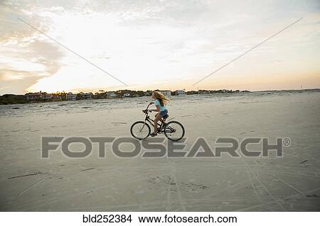 Picture - Caucasian girl riding bicycle on beach. Fotosearch