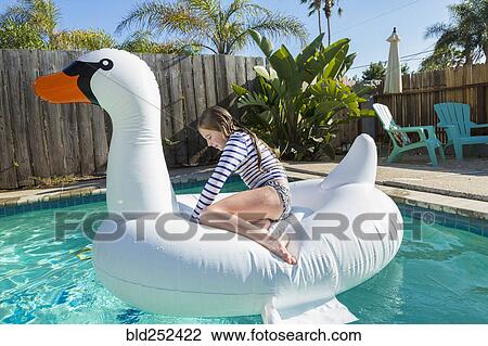 Caucasian girl sitting on inflatable swan in swimming pool View Large Photo Image Stock Image - Caucasian girl sitting on inflatable swan in swimming pool. Fotosearch