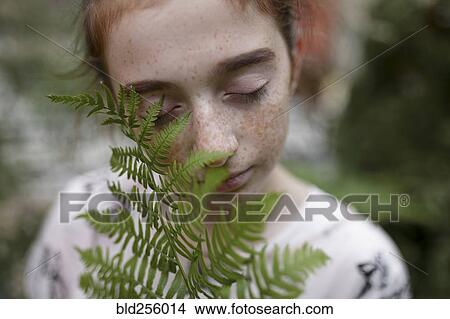 Picture - Caucasian girl smelling leaves. Fotosearch