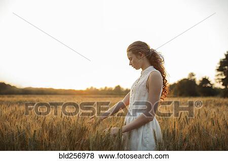 Caucasian girl standing in field of wheat View Large Photo Image Stock Photo - Caucasian girl standing in field of wheat. Fotosearch