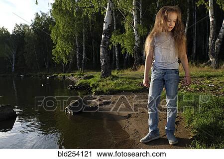 Stock Image - Caucasian girl standing near river. Fotosearch