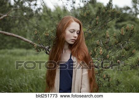 Stock Image - Caucasian girl standing near tree branch. Fotosearch