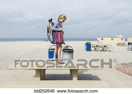 Stock Photograph - Caucasian girl standing on picnic table at beach. Fotosearch
